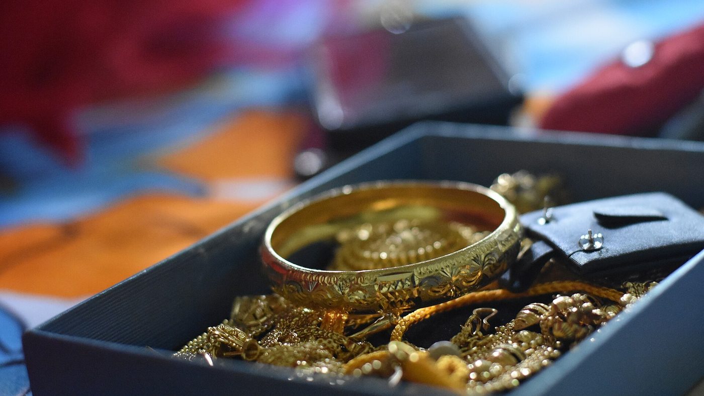 Gold bridal jewellery in an open case with a loupe and tweezers beside it