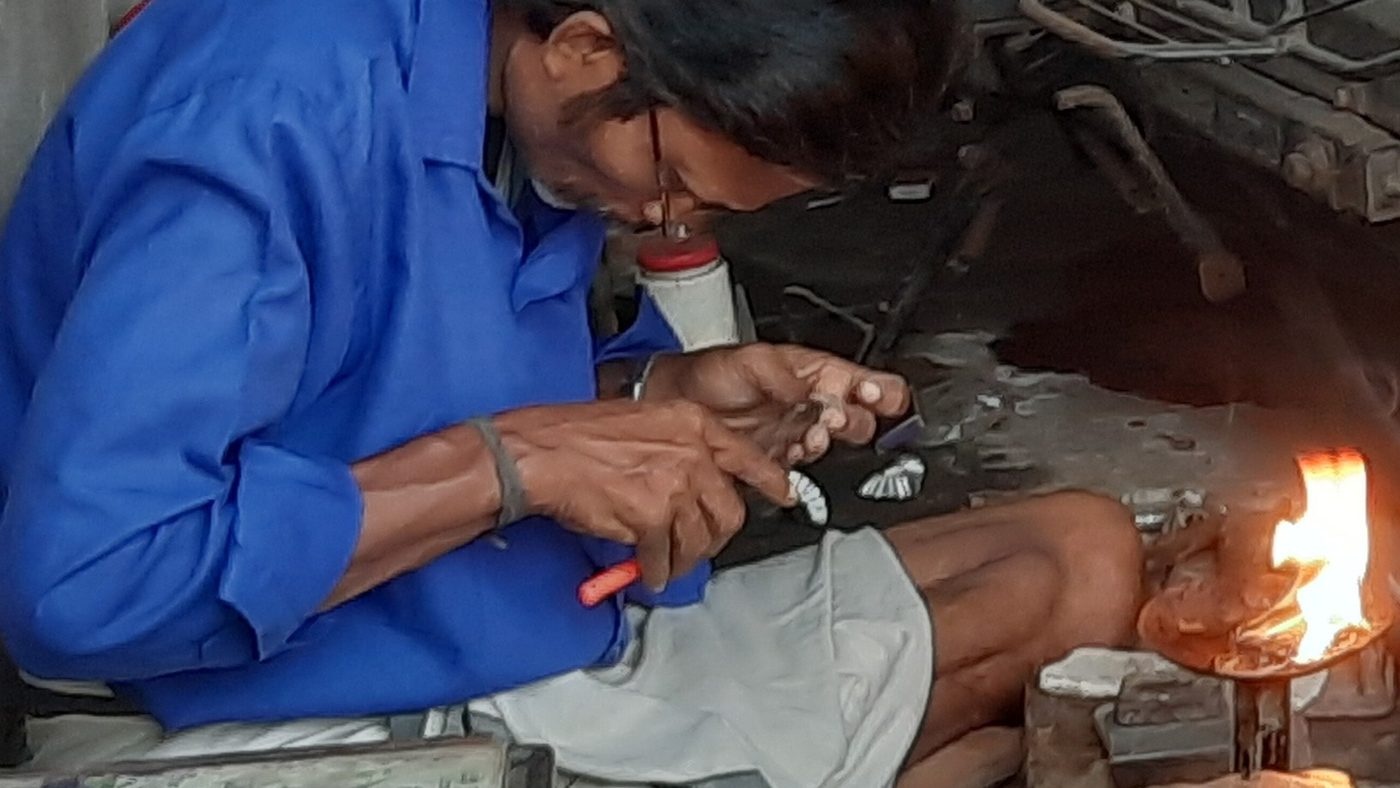 An Indian goldsmith working gold at his bench with a flame torch in Kollam, Kerala